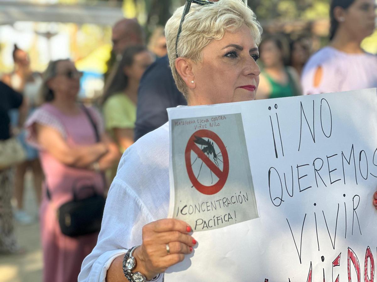 Una vecina de Coria del Río sostiene una pancarta con el mensaje &quot;No queremos vivir con miedo&quot; en la manifestación en Coria del Río contra el virus del Nilo.