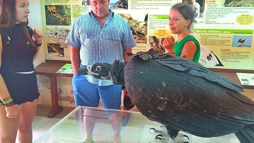 Varios asistentes a la jornada de puertas abiertas ante una maqueta de un buitre negro.