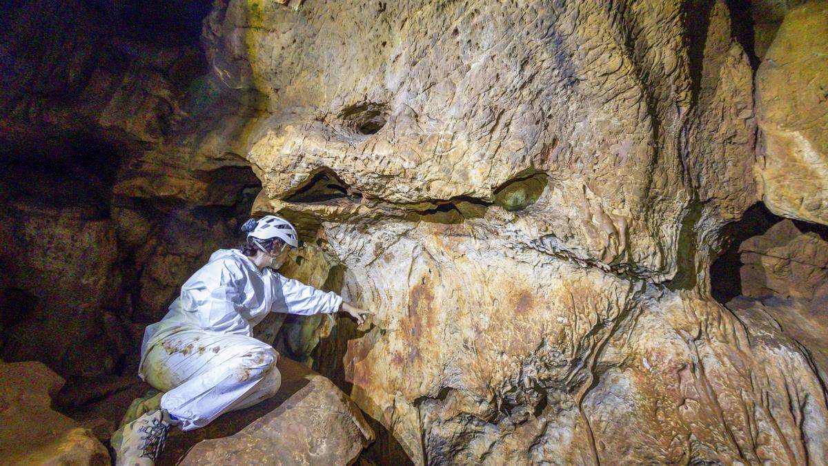 La arqueóloga señala una de las pinturas de la cueva de Maltravieso.