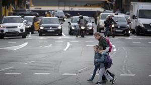 Un padre agarra a sus hijos para cruzar la calle de Aragó