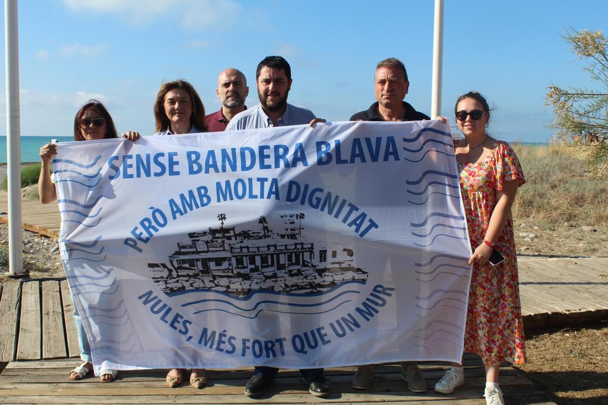 El alcalde de Nules, David García; junto a la concejala de Playas, M. José Esteban; y una representación de los miembros del actual gobierno municipal, con la bandera.