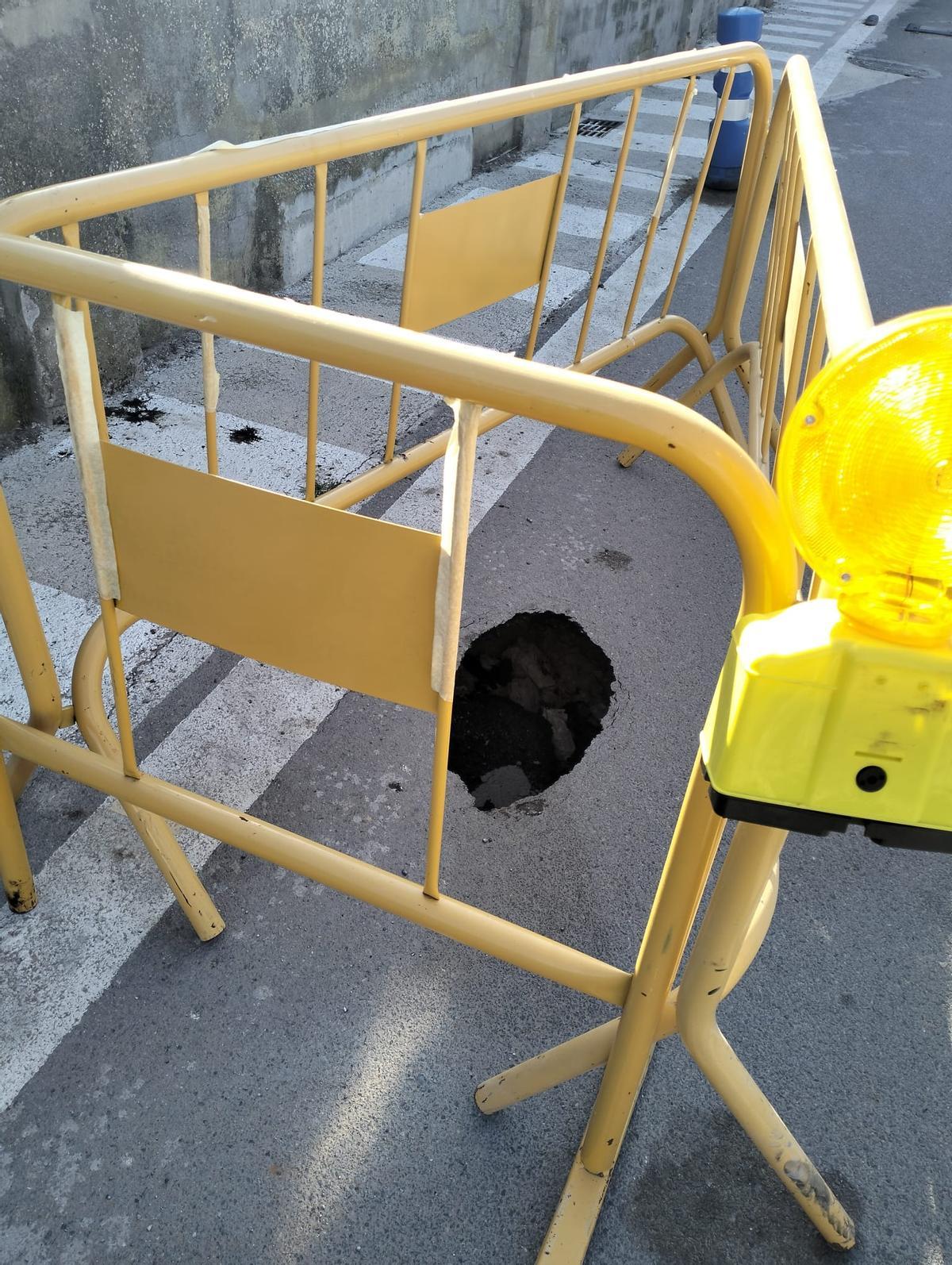 Un agujero en un lateral de la calzada protegido con vallas para evitar accidentes.