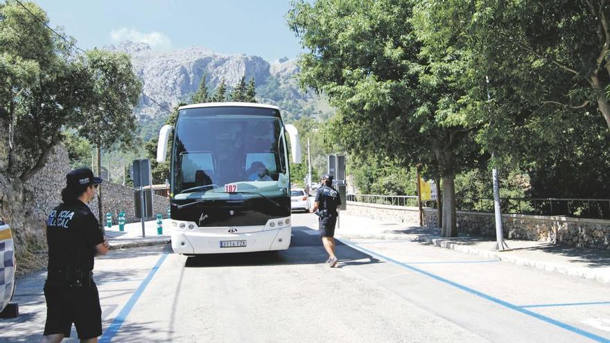 Varios agentes de policía controlando el acceso de autocares al paseo que da entrada a la cala, que será rotulado como zona verde y zona azul.