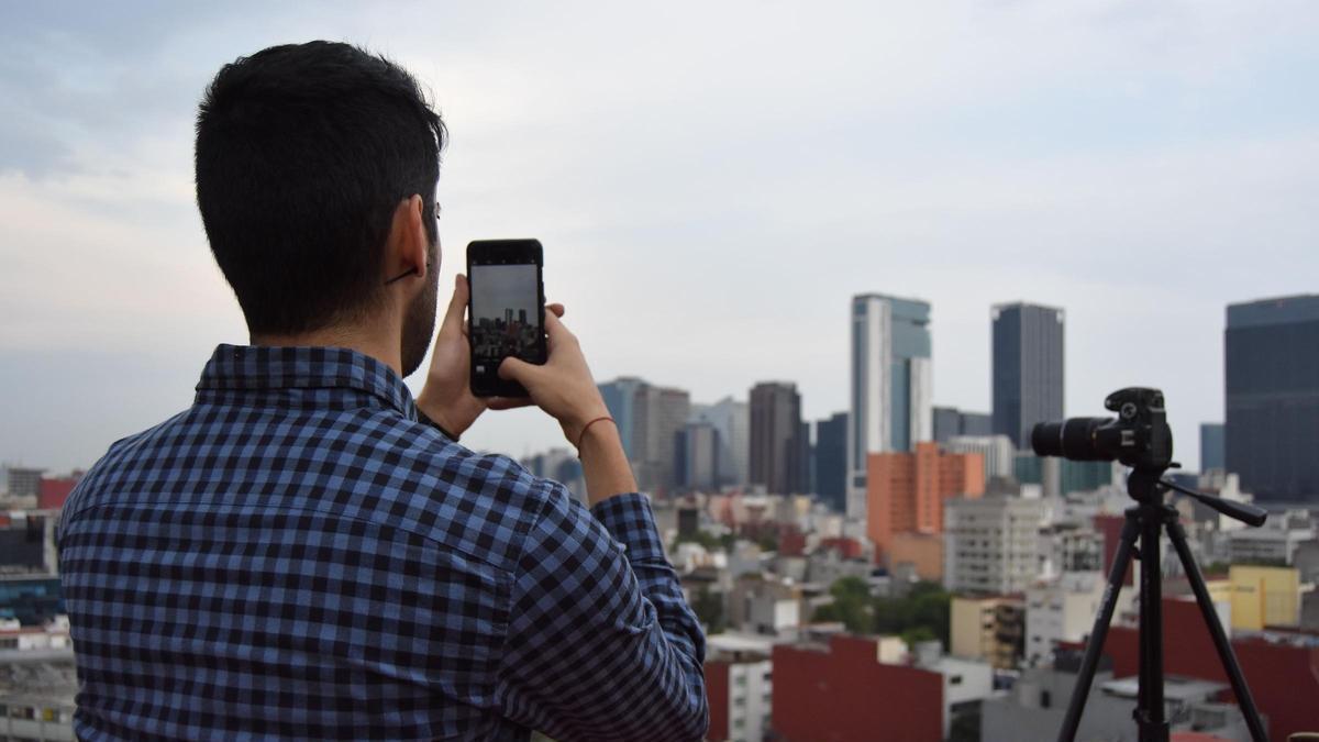 Una persona subida en su azotea con teléfono móvil y cámara para ver el eclipse