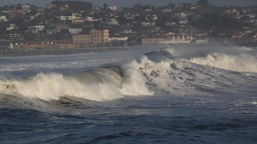 Numerosos curiosos se dan cita en el muro de Gijón para ver el oleaje