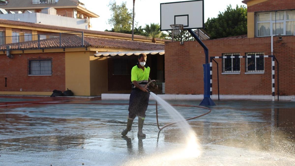 Un operario del servicio de limpieza de Fuengirola baldea la instalación deportiva de un colegio.