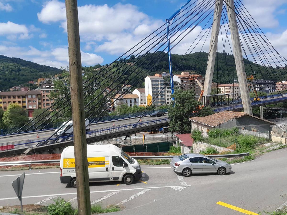 Tráfico siendo desviado por La Felguera en primer término, con el puente atirantado detrás, en obras, con un solo carril abierto.