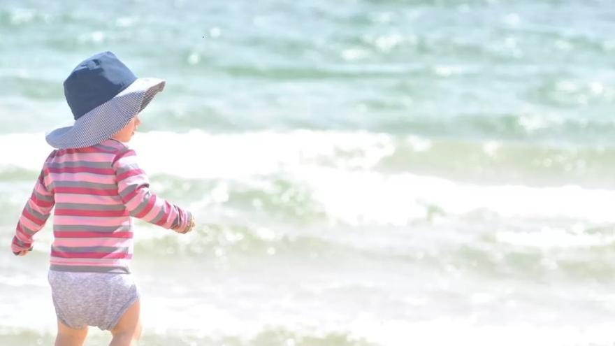 Un niño en la playa se protege del sol con un sombrero