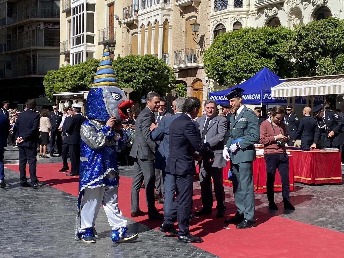 La mascota sardinera pasa junto a las autoridades hasta ocupar un asiento en el acto por San Patricio en Belluga.