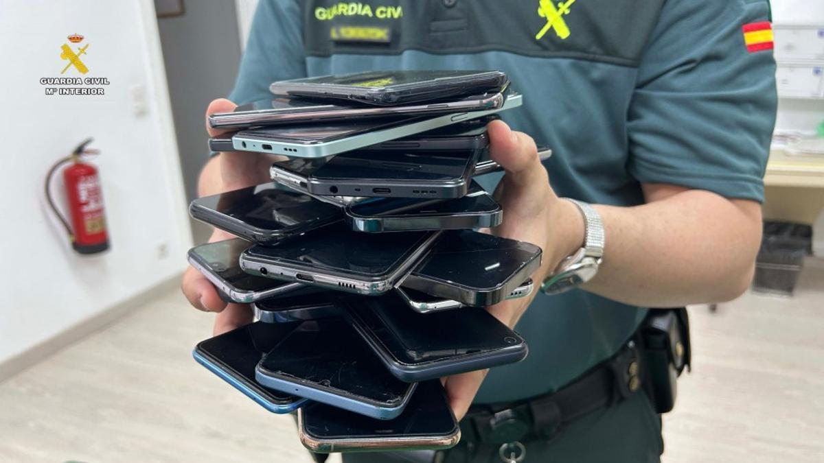 Un agente sostiene móviles robados en aglomeraciones.