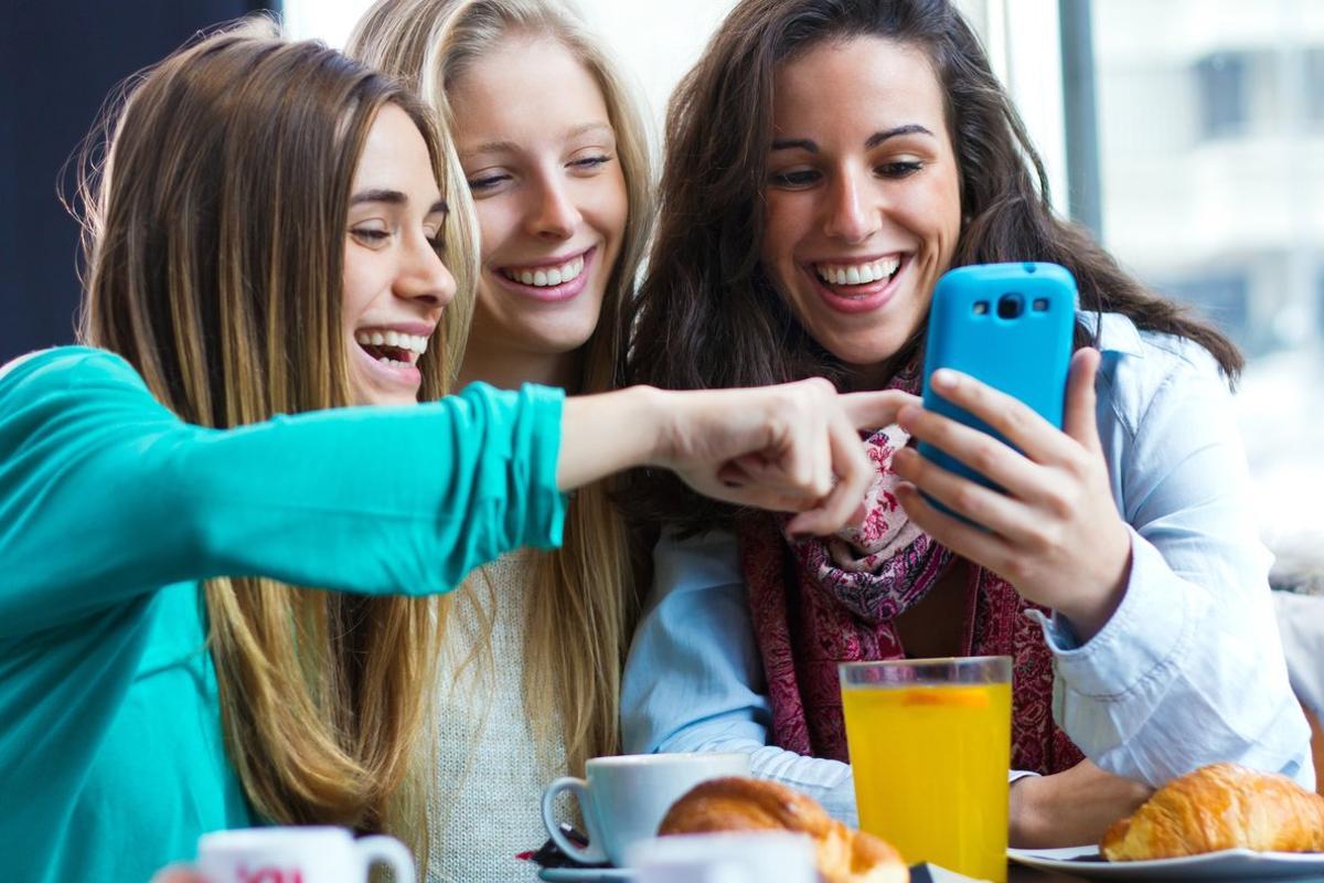 Tres chicas se divierten con el teléfono móvil.