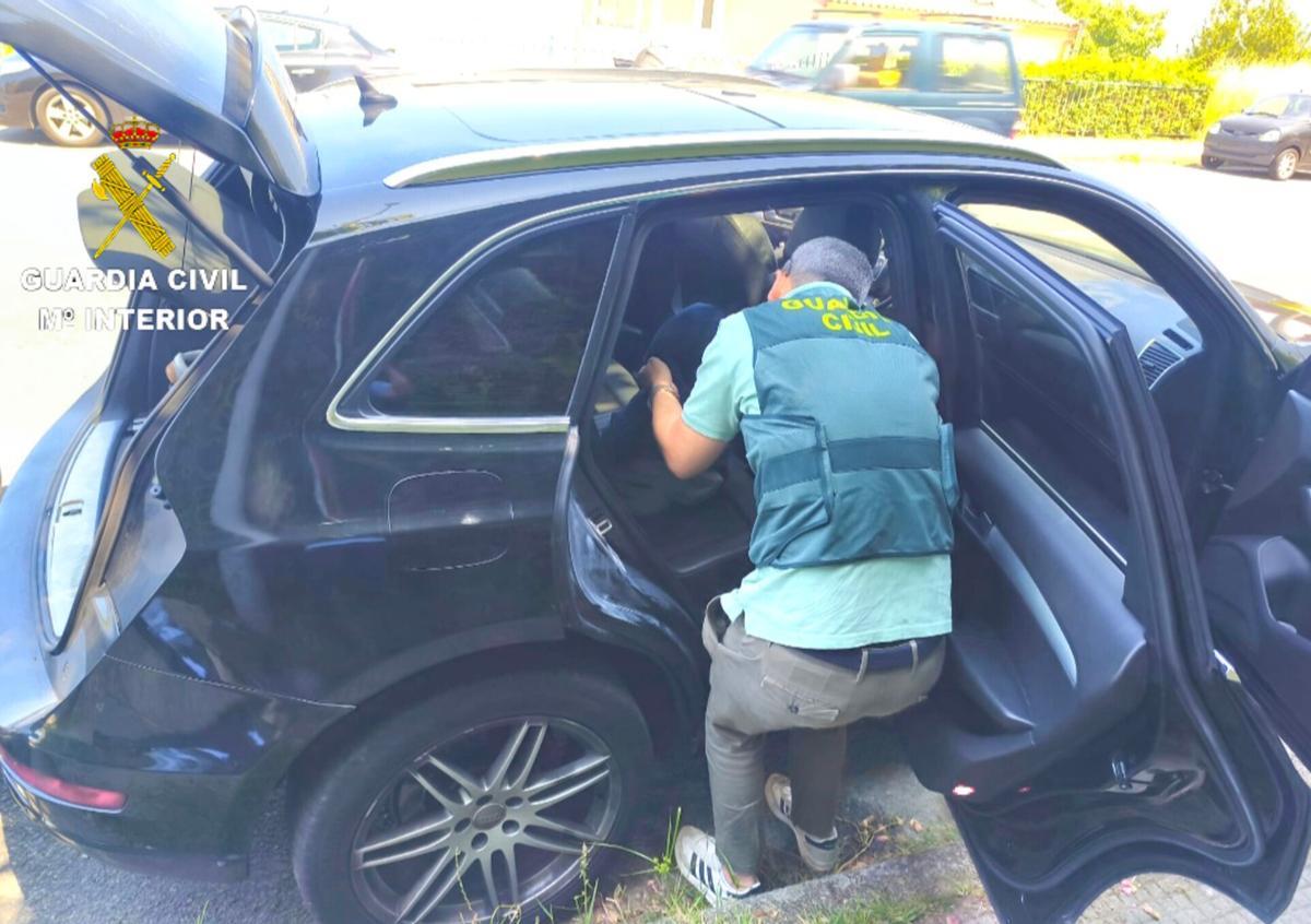 Un agente de la Guardia Civil registra un vehículo relacionado con los atracadores de una sucursal bancaria en Pazos de Borbén el pasado mes de mayo.