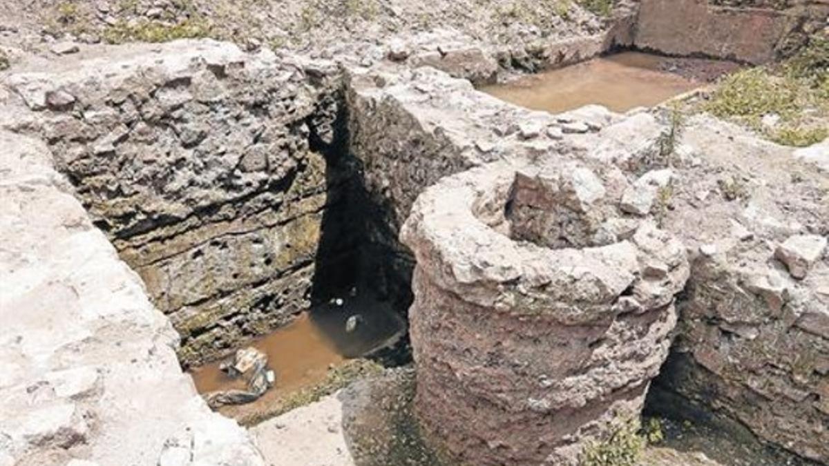 Sobre el área encharcada, un corte muestra los fangos que acabaron rellenando el foso de Barcino.