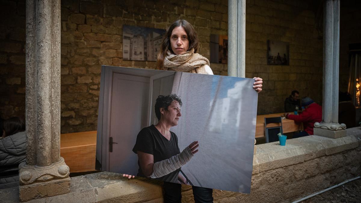 Maria Contreras, en el claustro de Santa Anna con una de las imágenes de su exposición sobre la ayuda que ofrece la parroquia.
