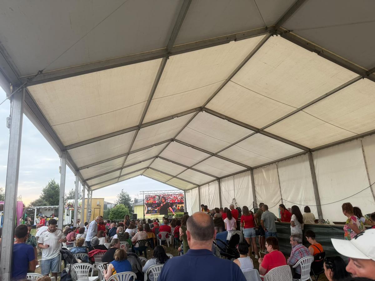 Los vecinos bajo la carpa de la fiesta con la pantalla gigante para disfrutar del partido de fútbol.