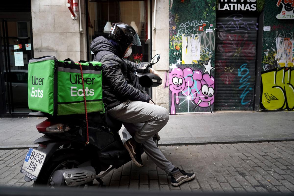 Un repartidor de UberEats espera un pedido en su motocicleta.