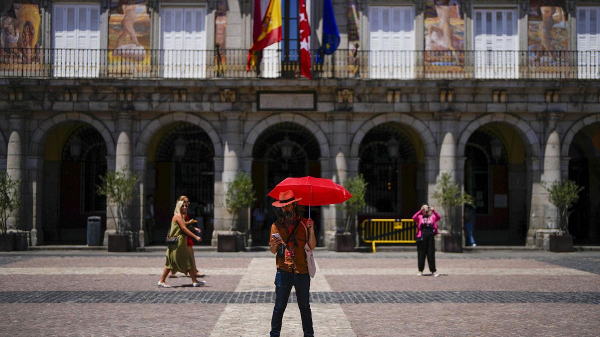 Un hombre se protege del calor con un paraguas en el centro de Madrid.