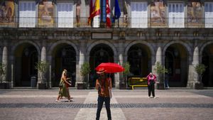 Un hombre se protege del calor con un paraguas en el centro de Madrid.