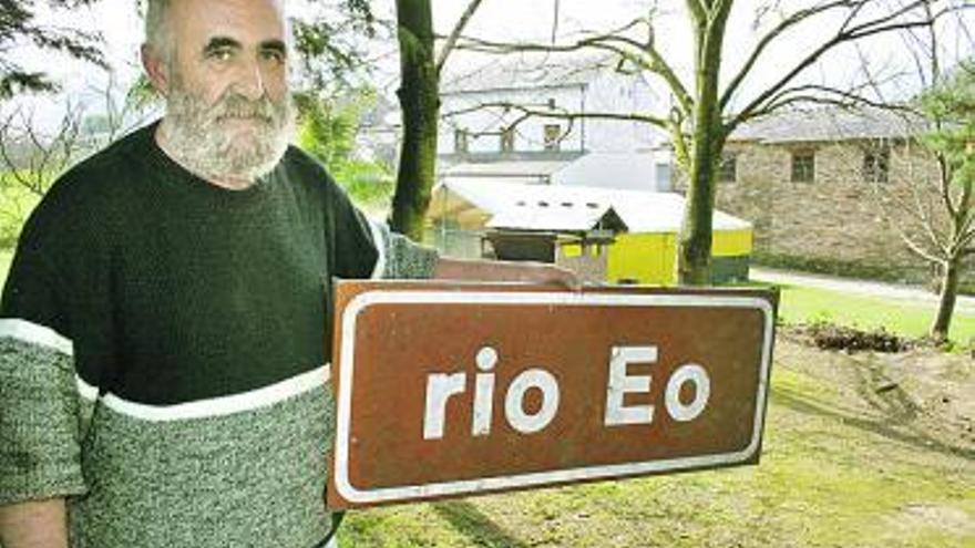 El gancheiro José Pérez, con el cartel del río.