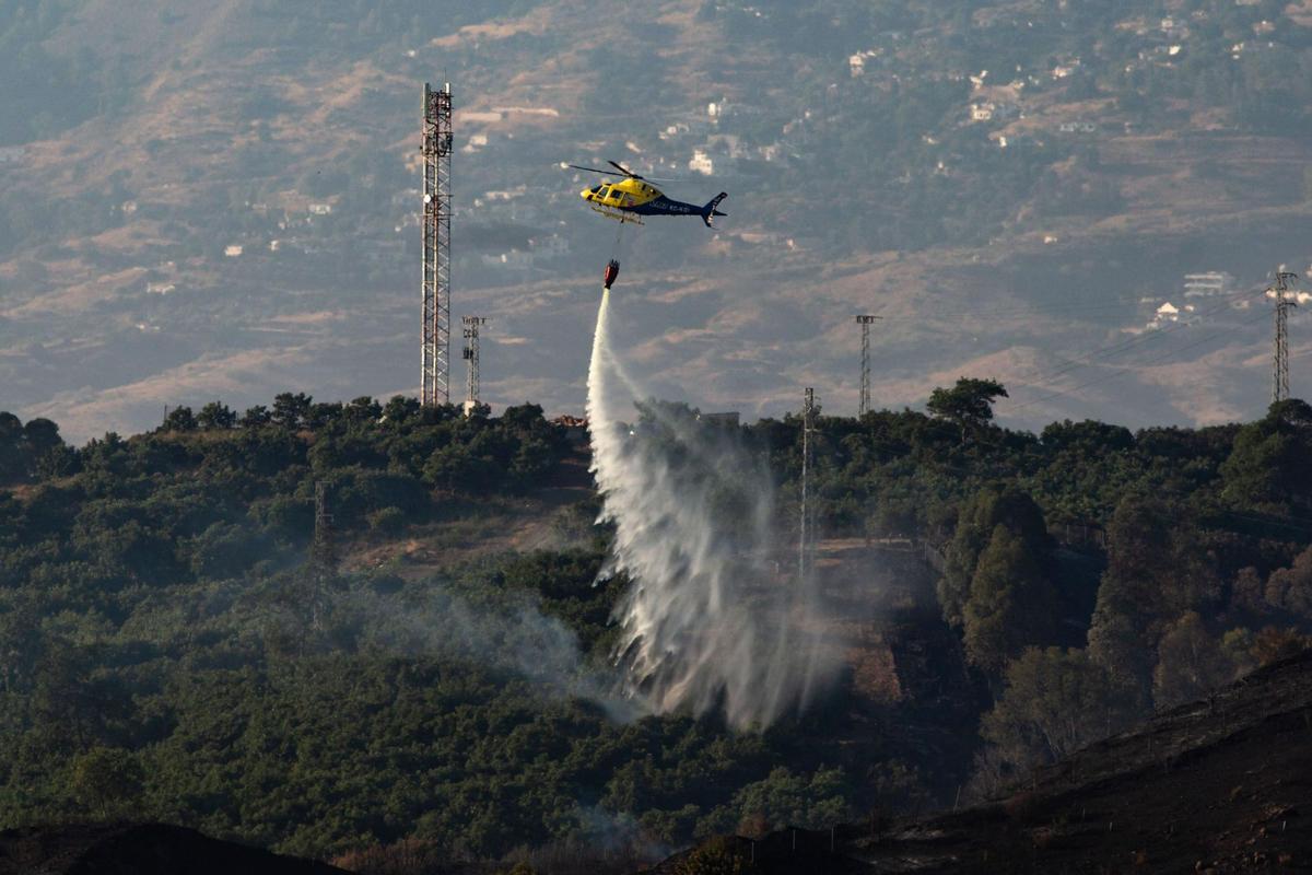 Un helicóptero trabaja en las tareas de extinción del incendio en la localidad malagueña de Mijas. EFE/Daniel Pérez