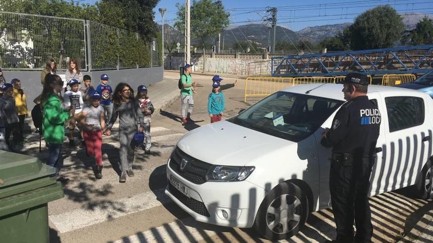 Varios niños escuchan las explicaciones del policía tutor ente un vehículo mal estacionado.