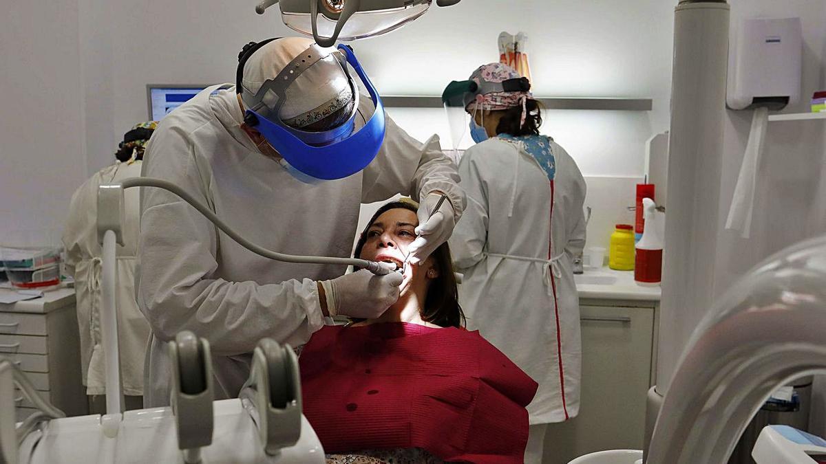 Rogelio Escamilla atiende a un paciente en su clínica dental de València, esta semana.   | M.A. MONTESINOS