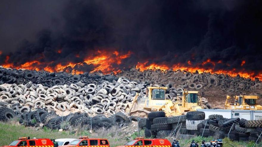 Bomberos y policías, ante el depósito en llamas.