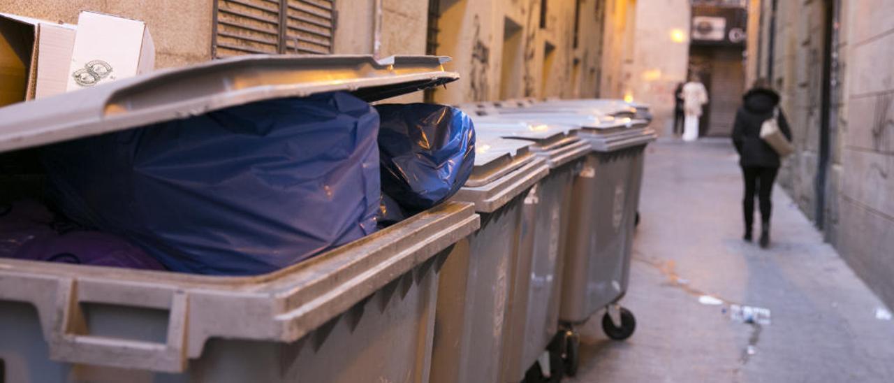 Contenedor lleno de basura a plena luz del día en una calle del centro de Alicante, el viernes.