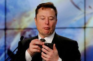 FILE PHOTO: Elon Musk looks at his mobile phone