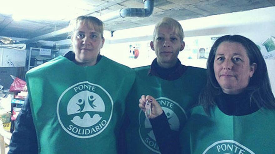 Tres miembros de Ponte Solidario con las llaves de su nuevo local en la estación de autobuses. // D.P.