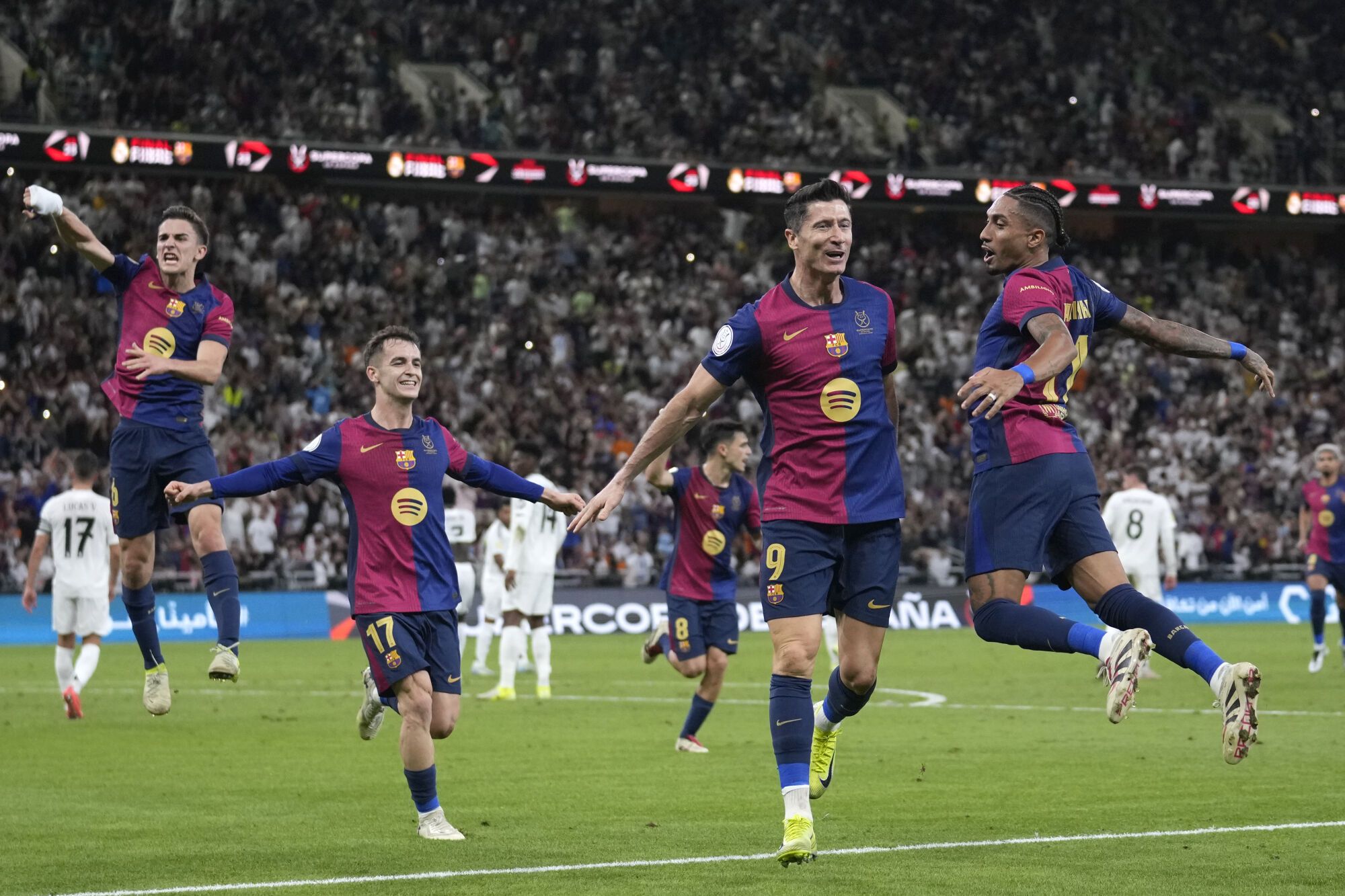 Barcelona's Robert Lewandowski, centre right, celebrates after scoring his side's second goal during the Spain Super Cup final soccer match between Real Madrid and Barcelona at King Abdullah Stadium in Jeddah, Saudi Arabia, Sunday, Jan. 12, 2025. (AP Photo/Altaf Qadri)