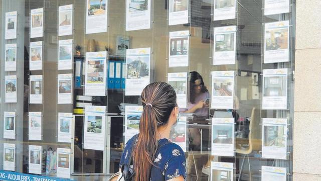 Una joven mira el escaparate de una inmobiliaria // Alba Villar
