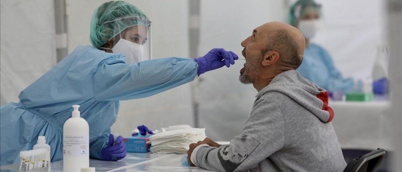 Una sanitaria hace un frotis bucal a un paciente durante la toma de muestras para realizar una PCR.