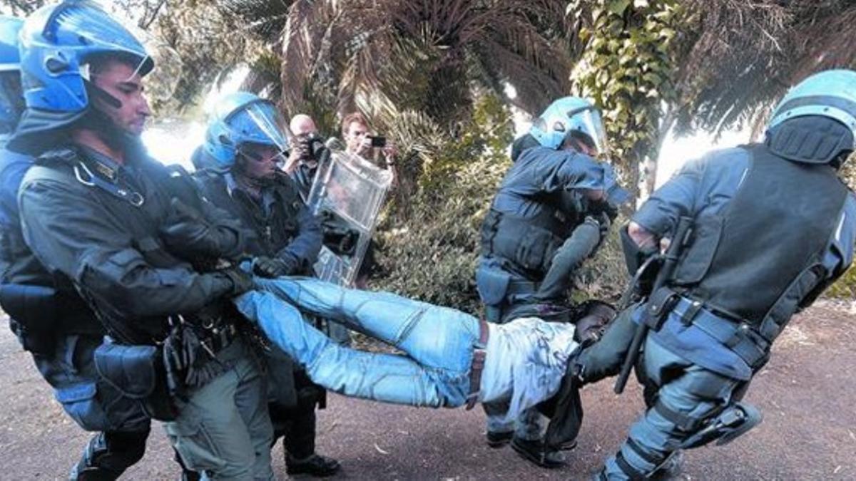 Cinco policías italianos desalojan a un inmigrante en Ventimiglia, este martes.