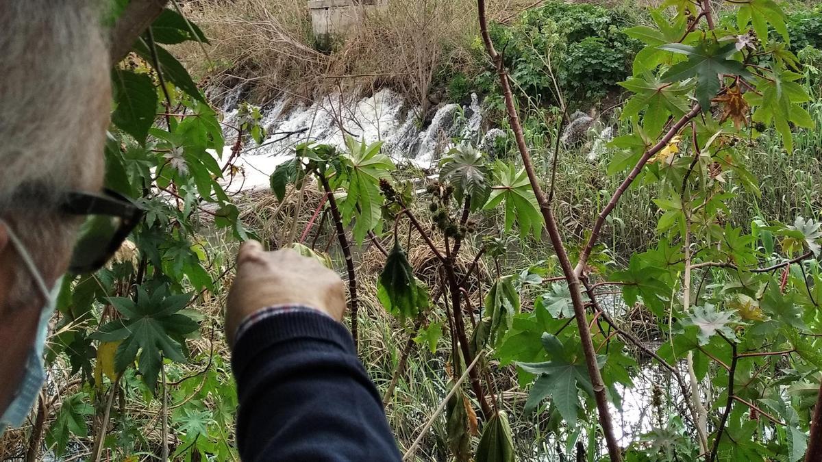Un vecino señala la cascada de aguas malolientes que terminan en el aliviadero del Guadalhorce.