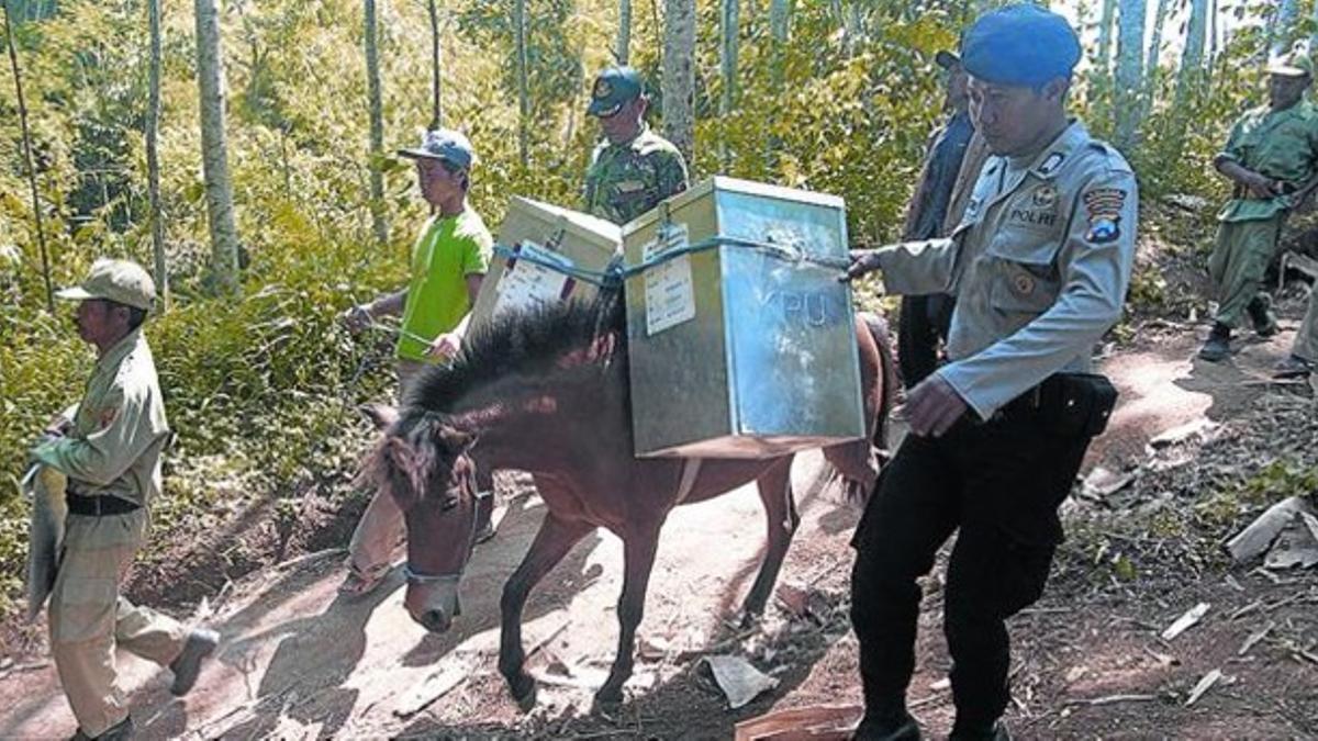 Policías y oficiales trasladan urnas electorales con caballos en Tlogosari, en el este de la isla de Java, ayer.