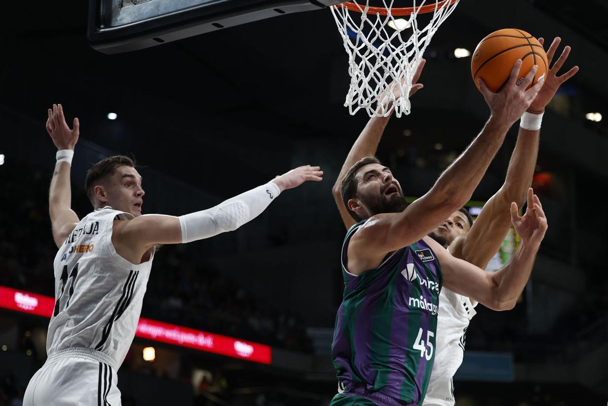 El pívot búlgaro del Unicaja David Kravish (c) entra a canasta ante la defensa de los jugadores del Real Madrid este domingo, durante un partido de baloncesto de la Liga Endesa, entre el Real Madrid y el Unicaja, en Madrid. EFE/ Daniel González