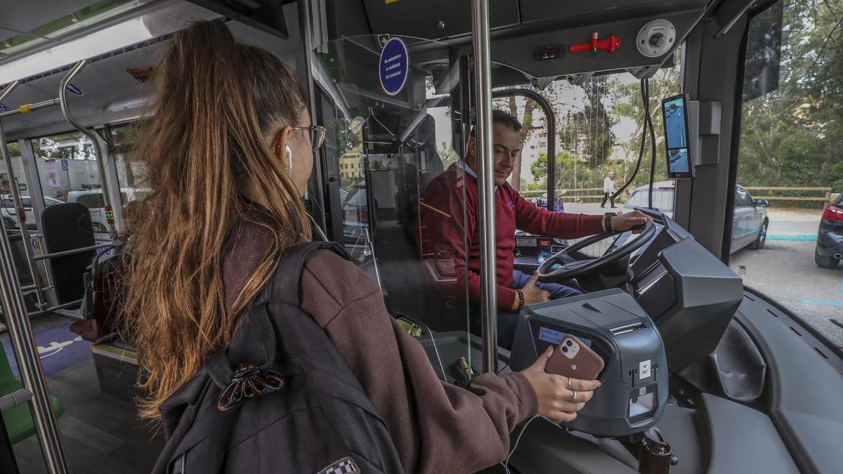 Una joven paga el billete esta semana con el móvil en un autobús urbano de Elche
