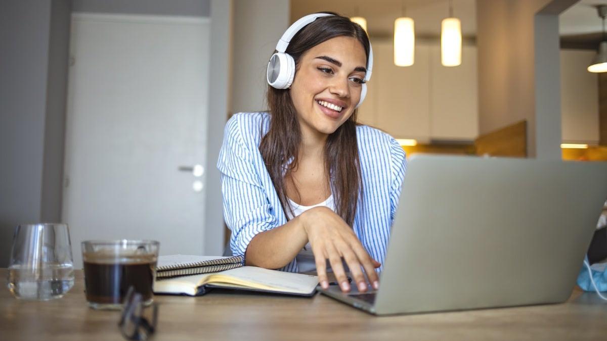 Chica sonriente estudiando con su ordenador en casa