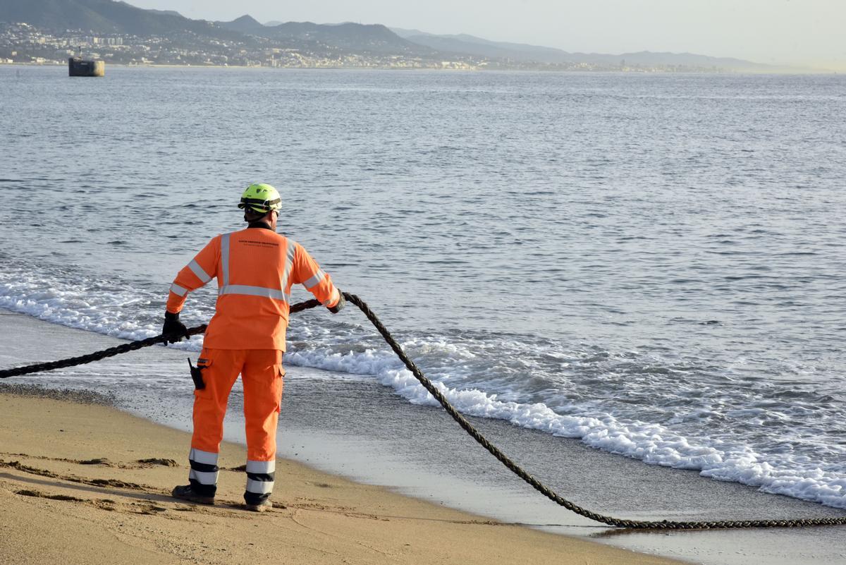 Un operario trasiega un cable durante las obras de extensión de conexiones de fibra óptica en la playa de Sant Adrià.
