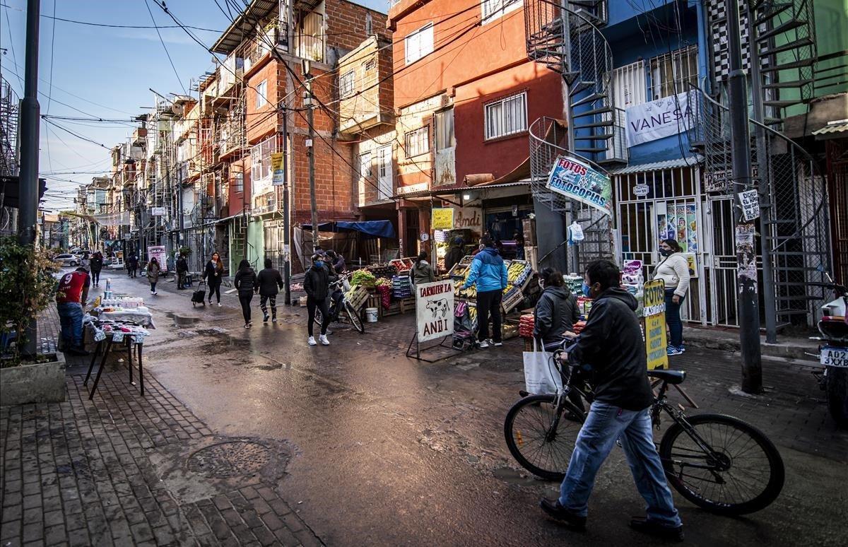 La gente camina por una calle y compra alimentos en los mercados locales en el barrio marginal Barrio 31.