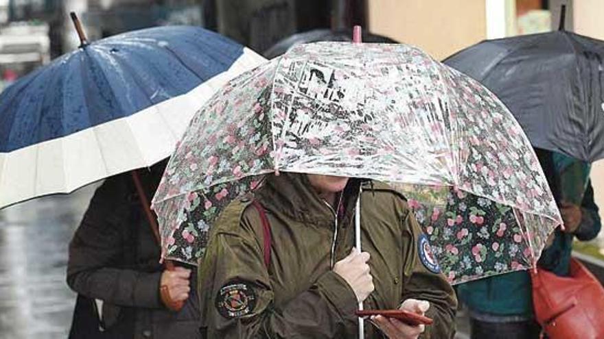 Varias personas se protegen de la lluvia en A Coruña.