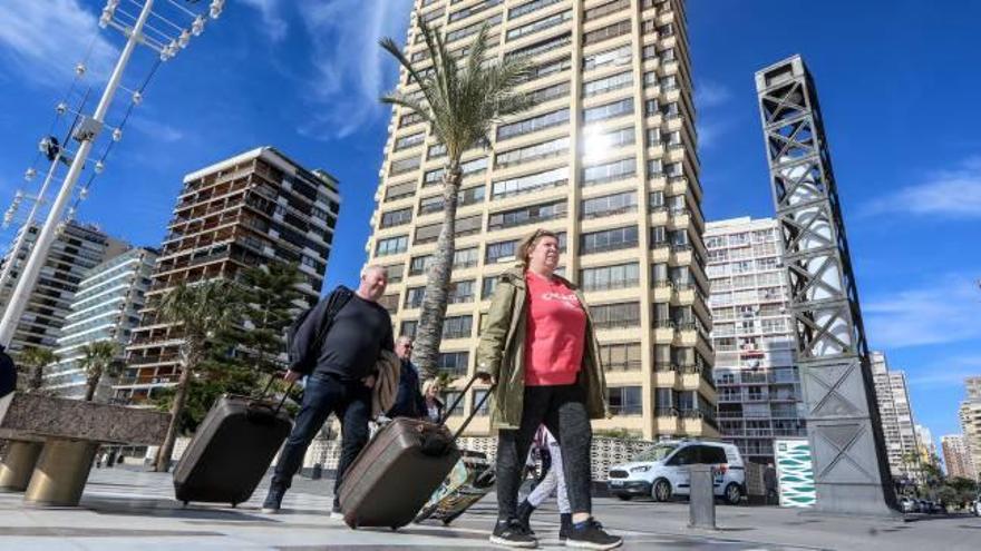 Dos turistas con sus maletas por el paseo de Levante de Benidorm.