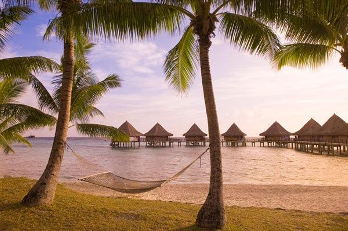 Hamaca en una de las playas del atolón con las cabañas de un hotel al fondo.
