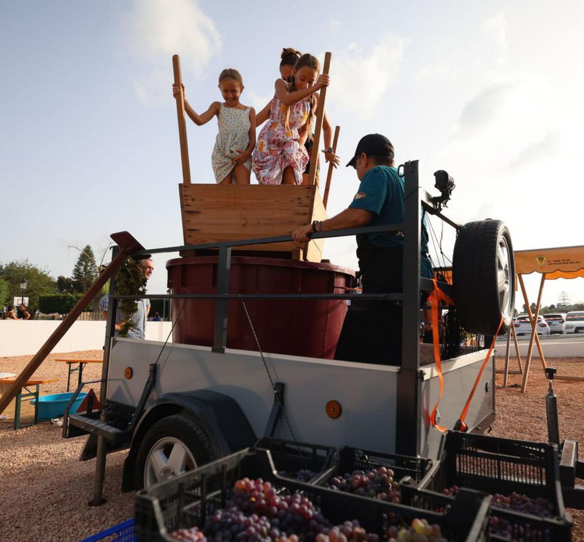 Dos niñas, acompañadas de su madre, pisan las uvas . | TONI ESCOBAR