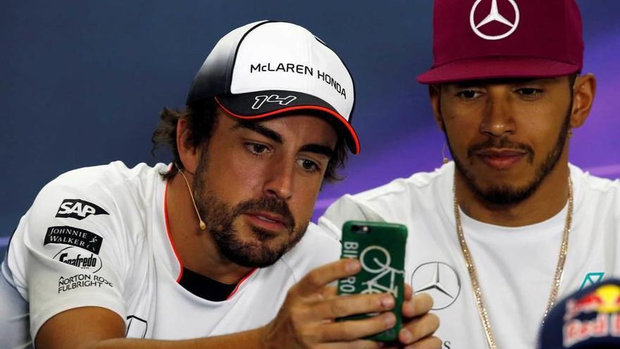 Fernando Alonso muestra una imagen a Lewis Hamilton durante una rueda de prensa.