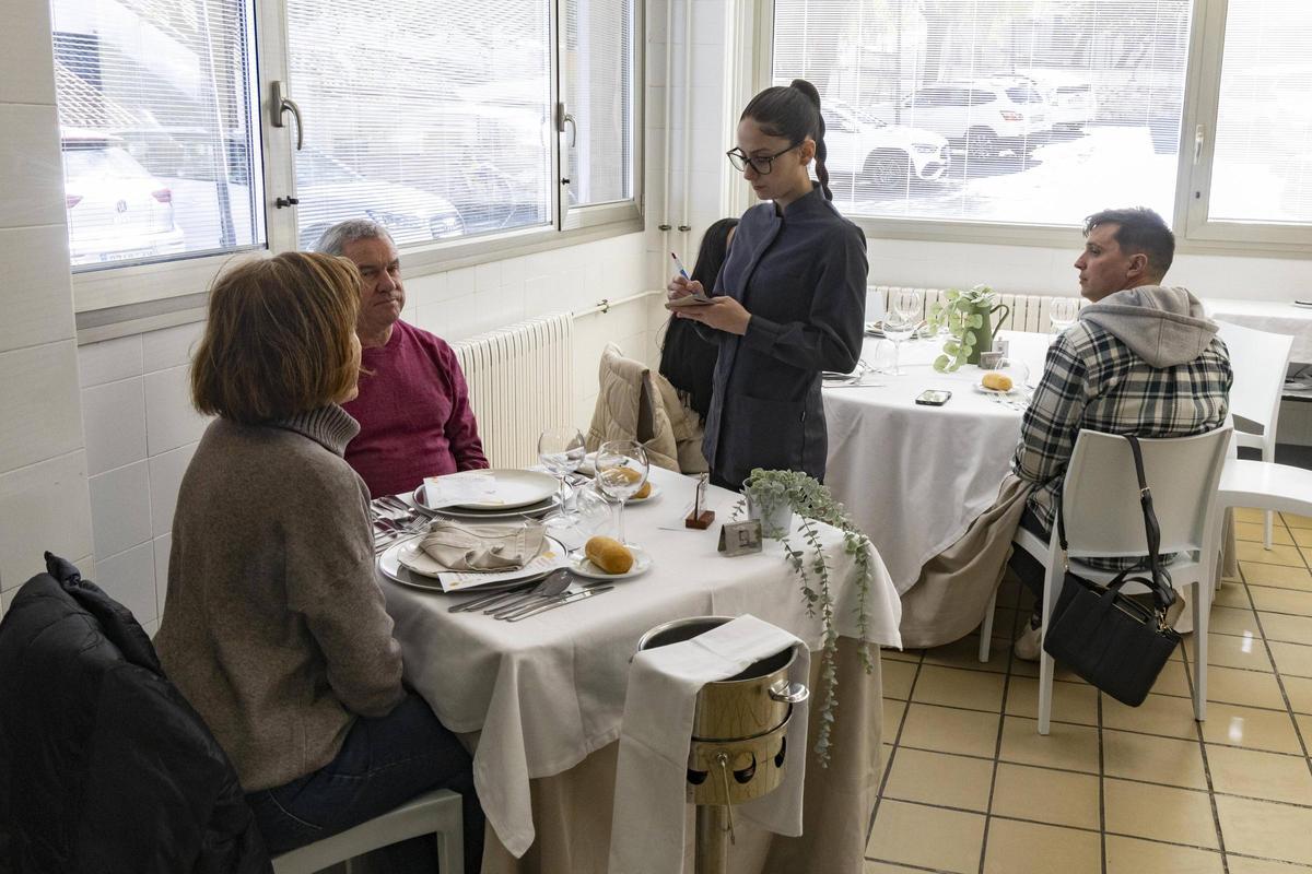 Una estudiante de Servicios de restauración atiende una mesa en el restaurante del instituto.