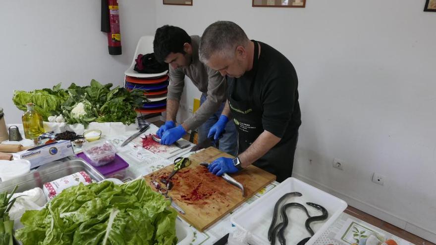 Dos participantes en el taller de &#039;espinagades&#039; sacrificando las anguilas