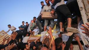 Los palestinos desplazados recogen la ayuda alimentaria que entró en el sur de la Franja de Gaza a través del Programa Mundial de Alimentos de las Naciones Unidas en la zona de Wadi Gaza, en el centro de Gaza.
