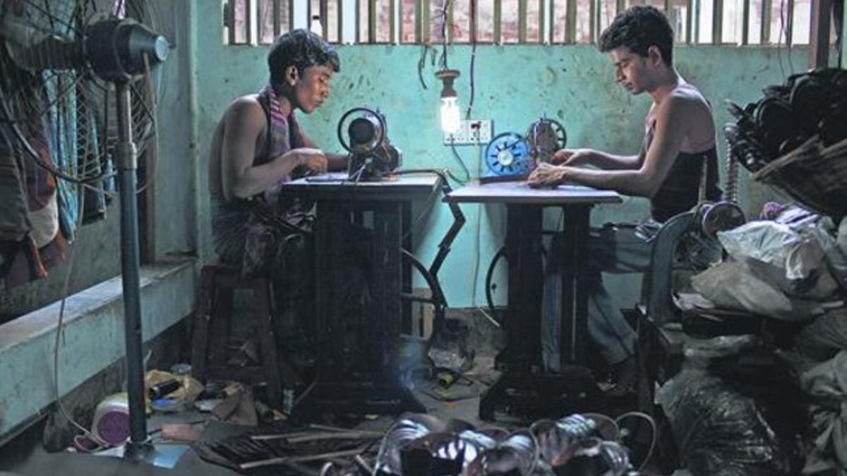 Dos chicos trabajancon sendas máquinas de coser, en uno de los talleres de Dacca, la capital de Bangladés.